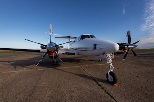 A sleek private propeller plane parked on a concrete runway under a clear blue sky.