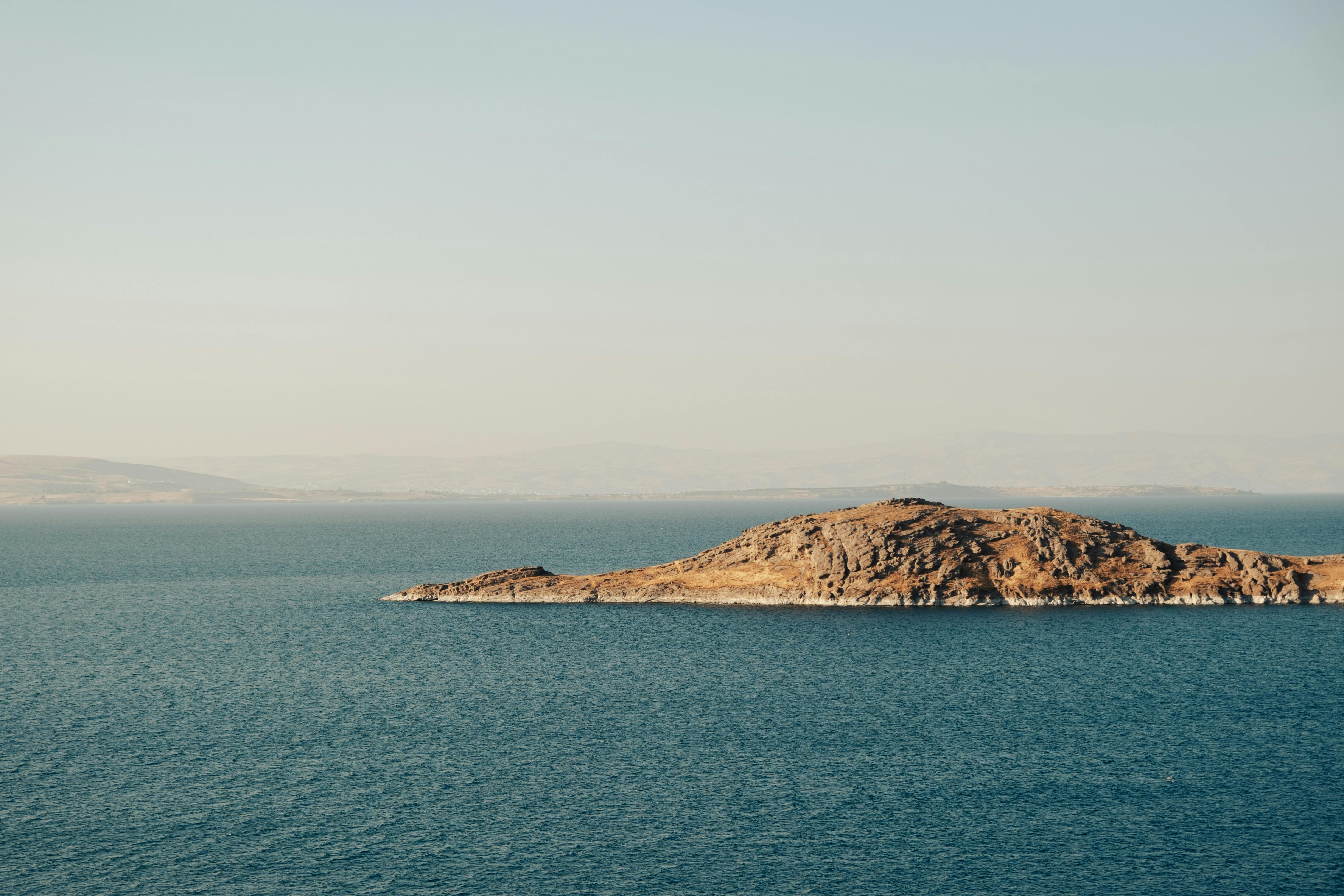 Peaceful distant view of an island surrounded by calm blue sea under clear sky.