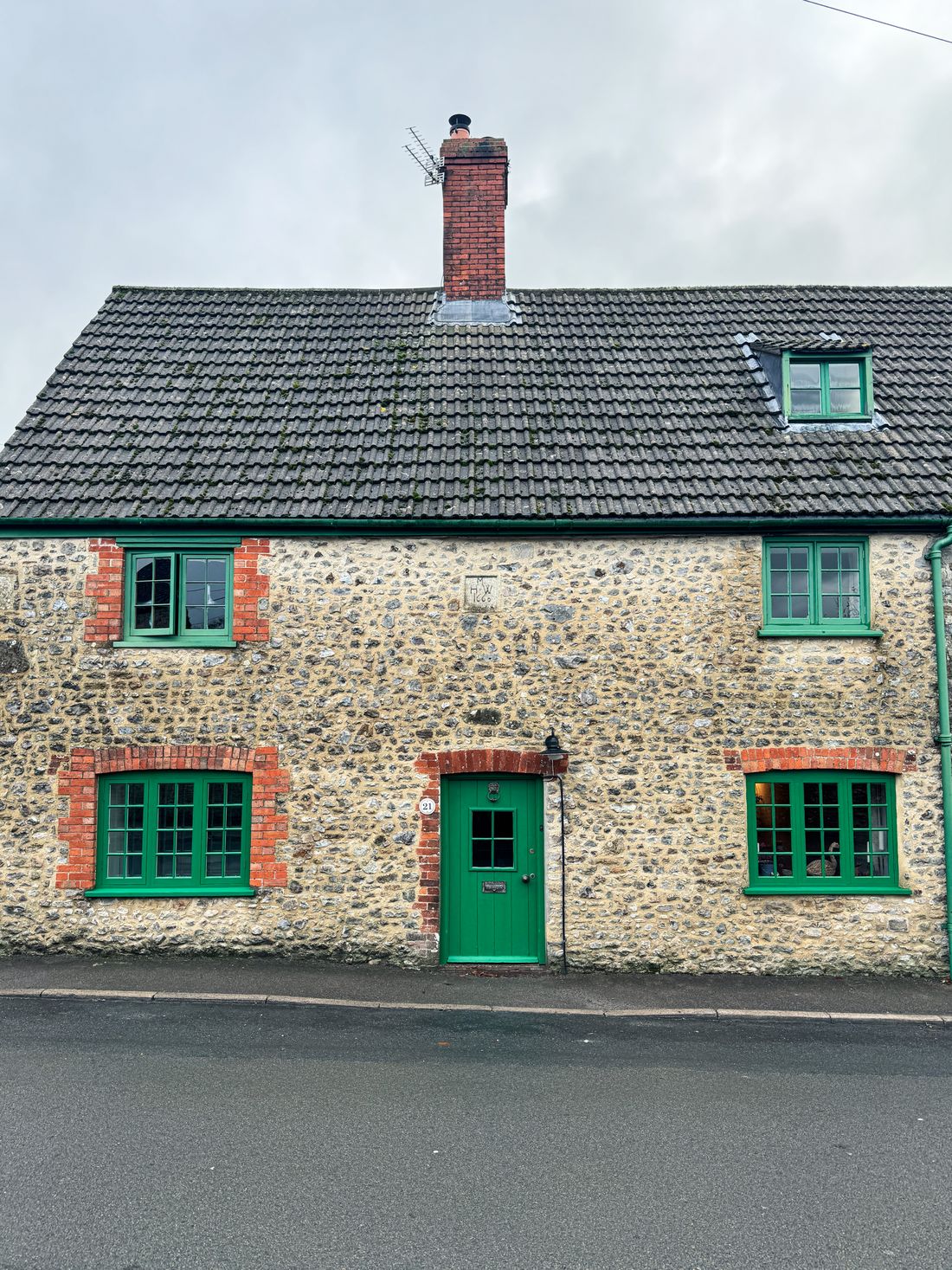 A stone cottage with green painted door and window frames, England