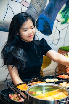 Young woman enjoying a hotpot meal indoors in Hà Tĩnh, creating a cozy atmosphere.