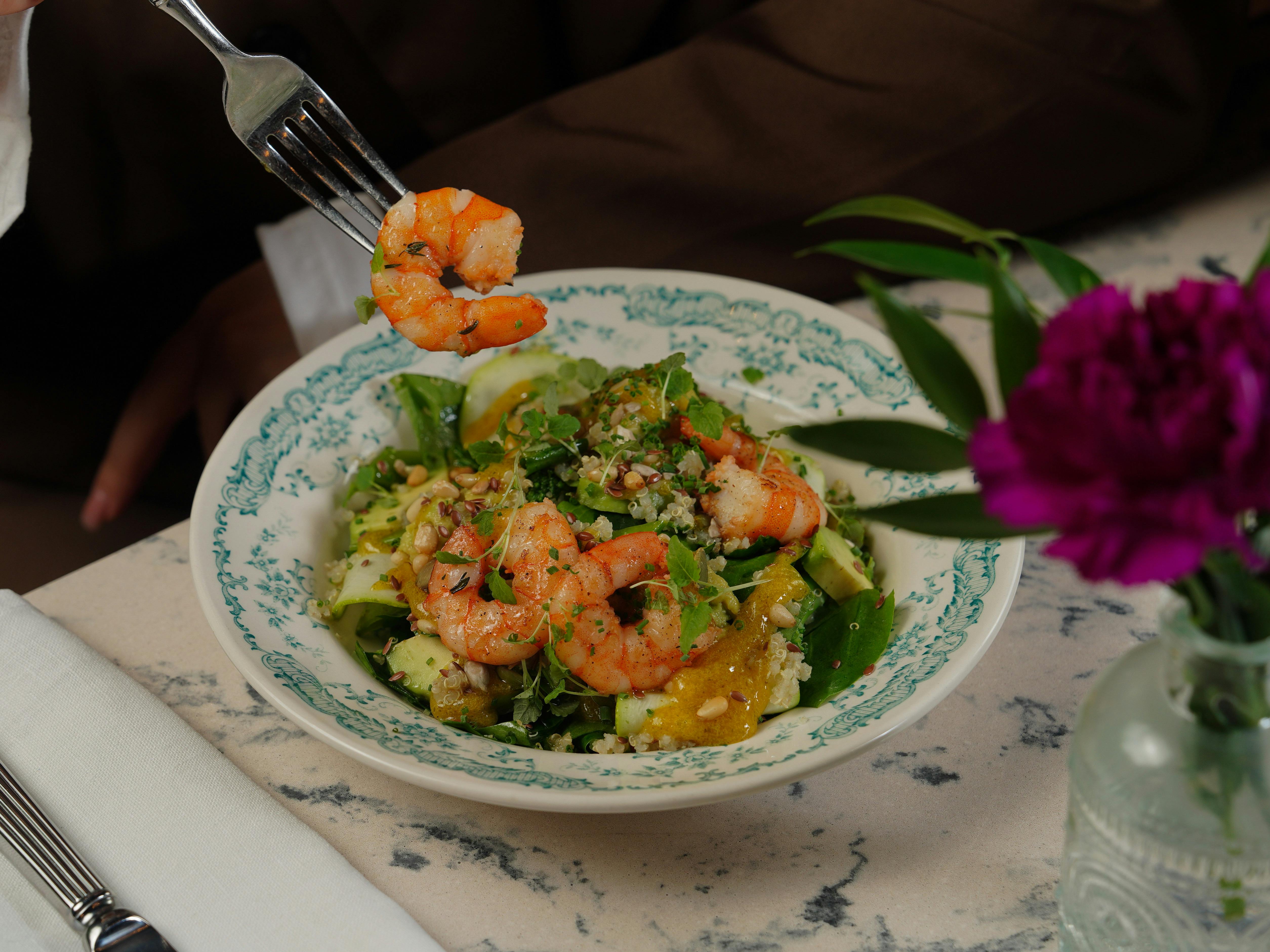 A gourmet shrimp salad with fresh greens served elegantly on a marble table.