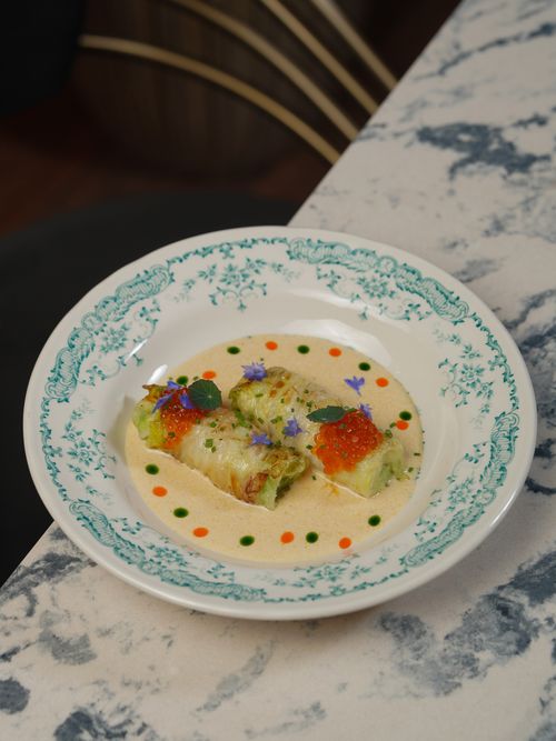 Free Elegant dish of stuffed cabbage with caviar and edible flowers in creamy sauce. Stock Photo