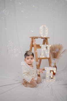 Cute baby celebrating first birthday with decorative lights and bubbles.