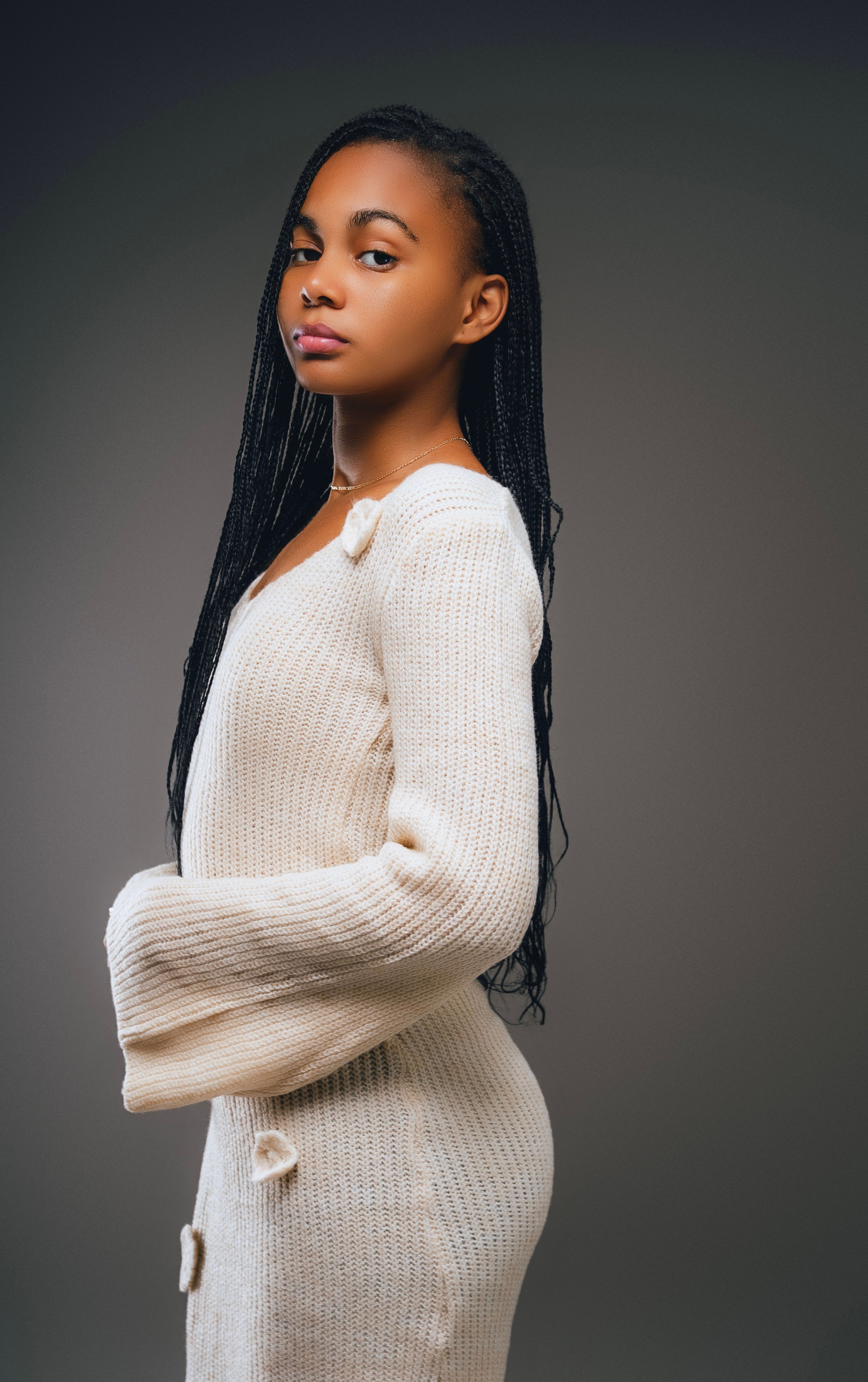 Profile portrait of a woman wearing a white sweater against a neutral backdrop.