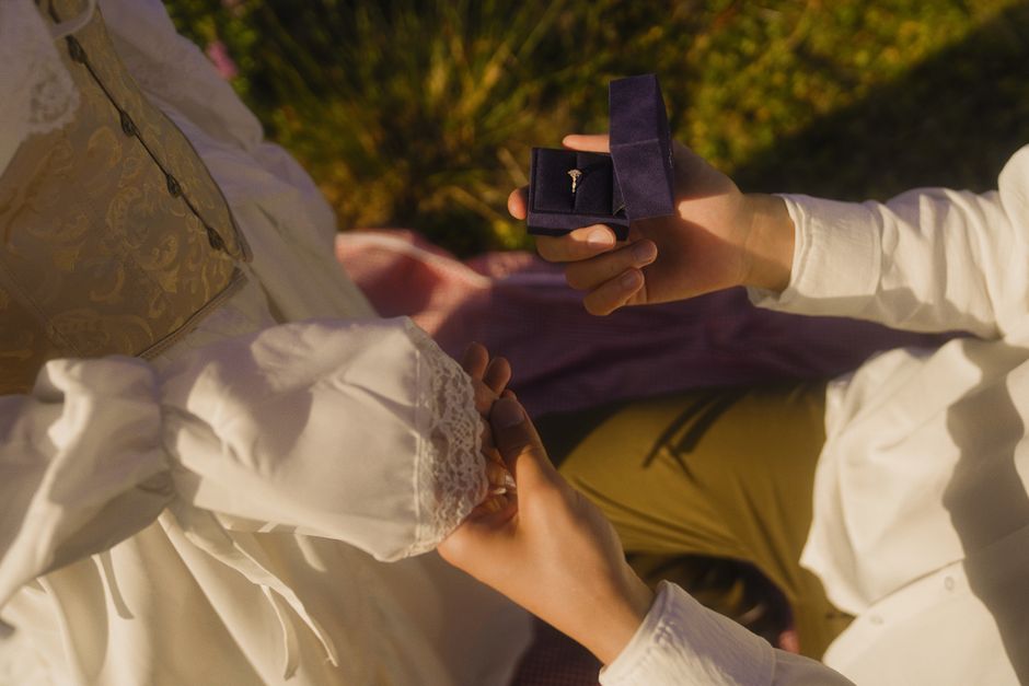 A diverse, modern couple celebrating a heartfelt proposal in an intimate outdoor setting A diverse, modern couple celebrating a heartfelt proposal in an intimate outdoor setting
