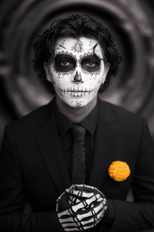 Free Close-up of a person in Day of the Dead makeup wearing formal black attire and yellow marigold accent. Stock Photo