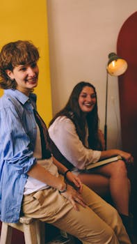 Two young women laughing and chatting in a cozy setting indoors.