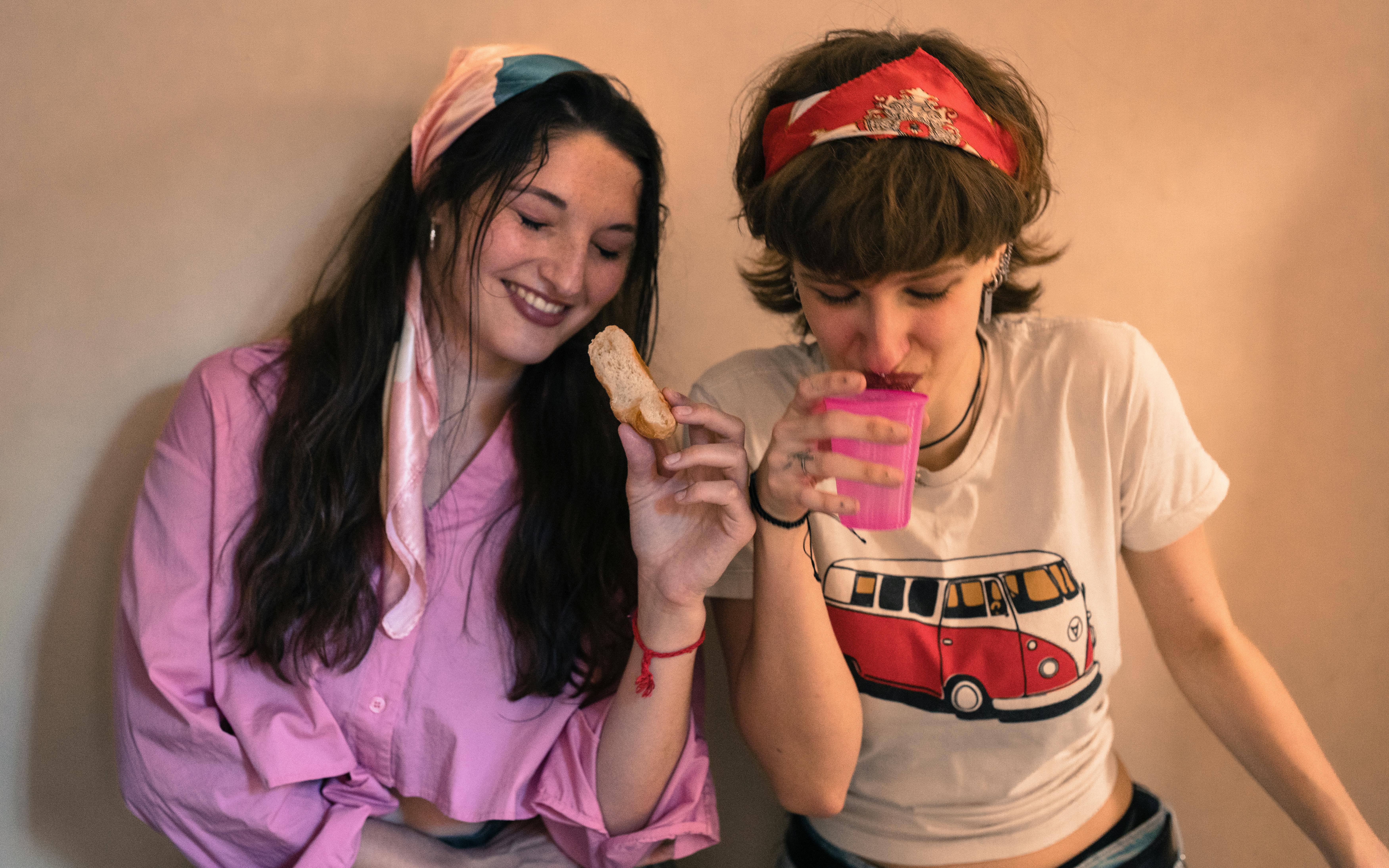 De franc Dues dones comparteixen un moment d'alegria a l'interior, prenent begudes i menjant. Foto d'estoc