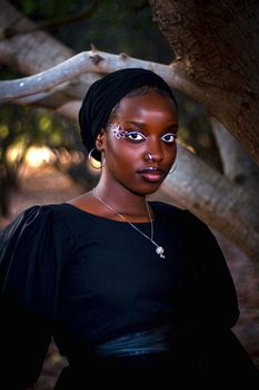 A striking portrait of a woman with creative makeup in a natural setting.