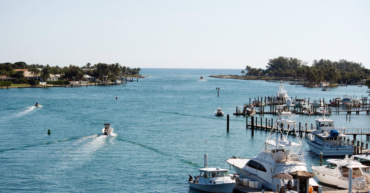 A picturesque scene of yachts and boats docked at Jupiter Inlet, FL, under a clear sky.