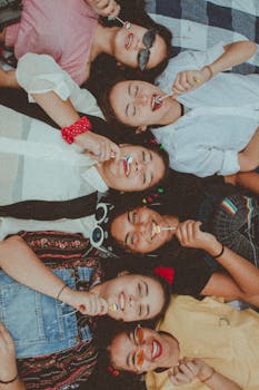 Joyful group of diverse women enjoying a sunny picnic with lollipops, showcasing friendship and fun.