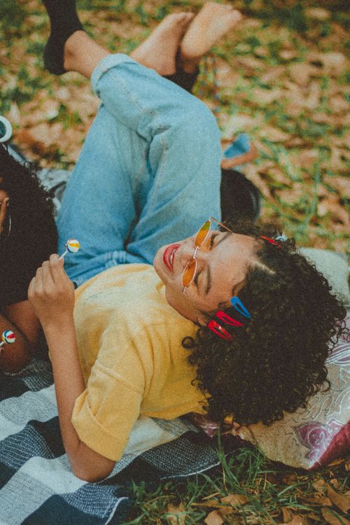 Free Smiling woman with curly hair and sunglasses enjoying a fall picnic outdoors. Stock Photo