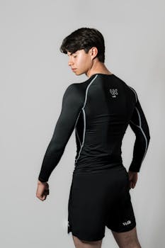 Athletic young man in black sportswear, poised and confident, showcasing fitness apparel.