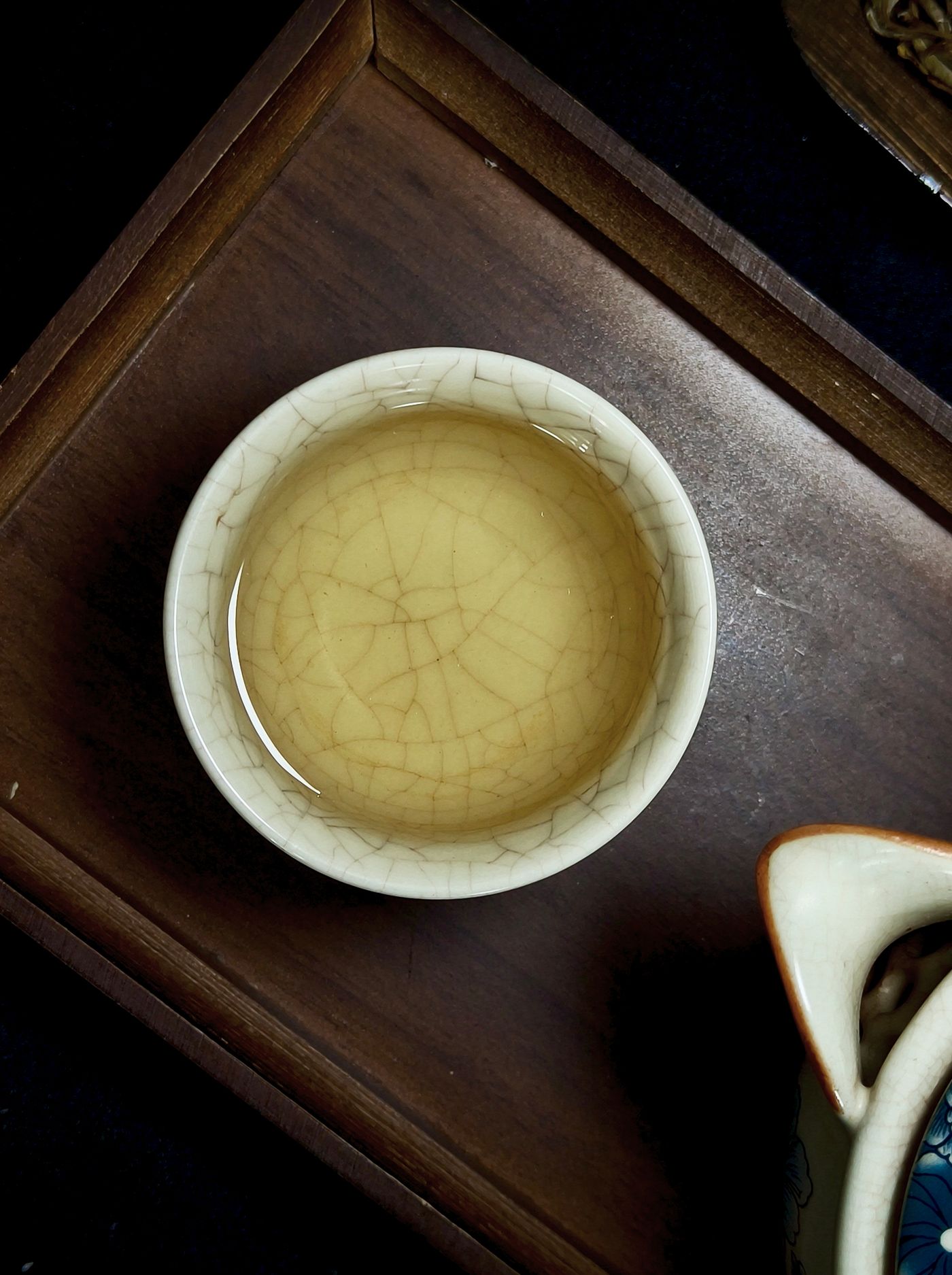 A ceramic tea cup on a wooden tray seen from above.