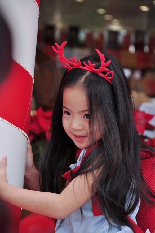 Free Young girl wearing reindeer antlers, celebrating festive holiday season indoors. Stock Photo