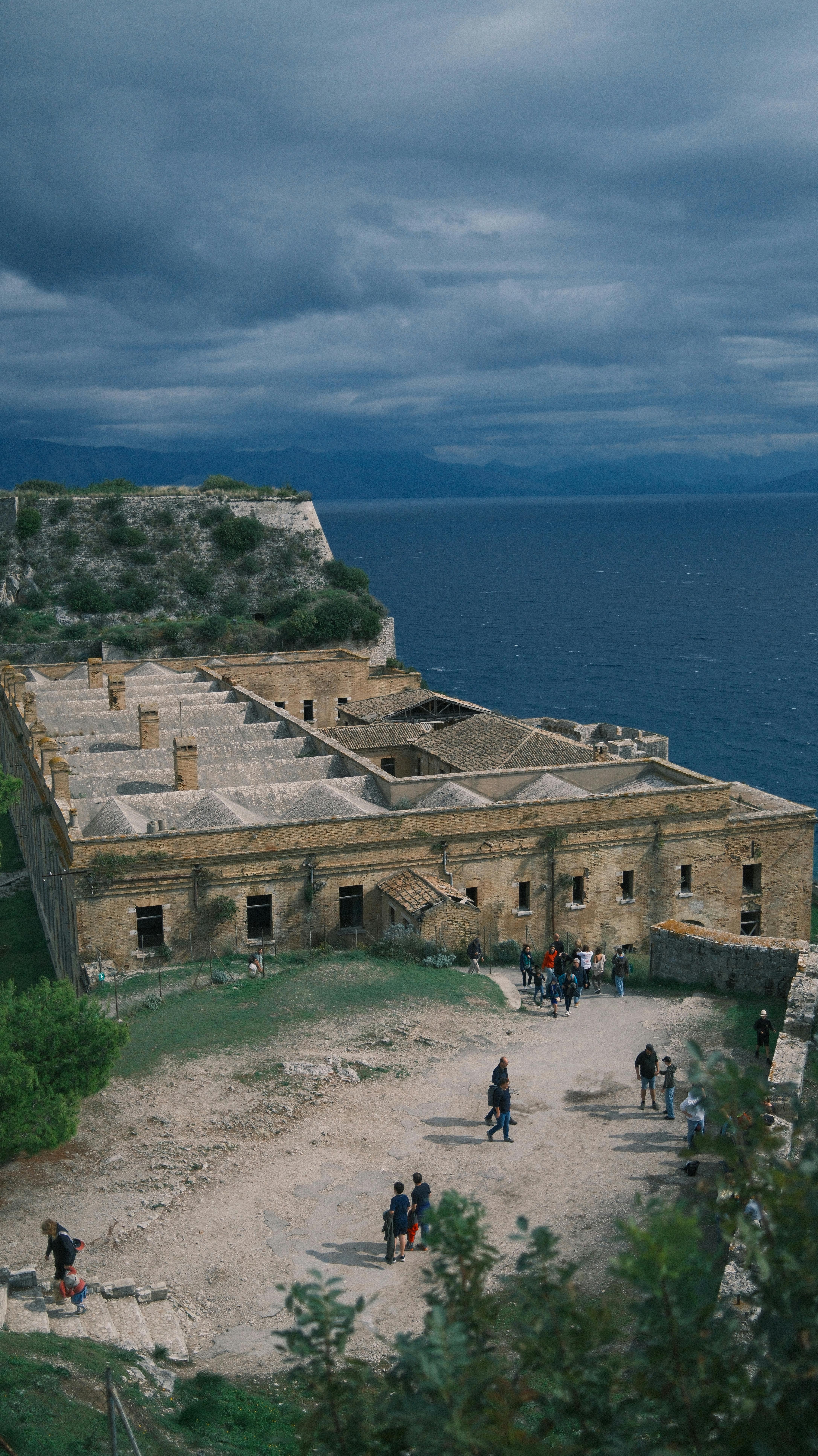 A stunning aerial view of a historic stone fortress by the sea under dramatic skies.
