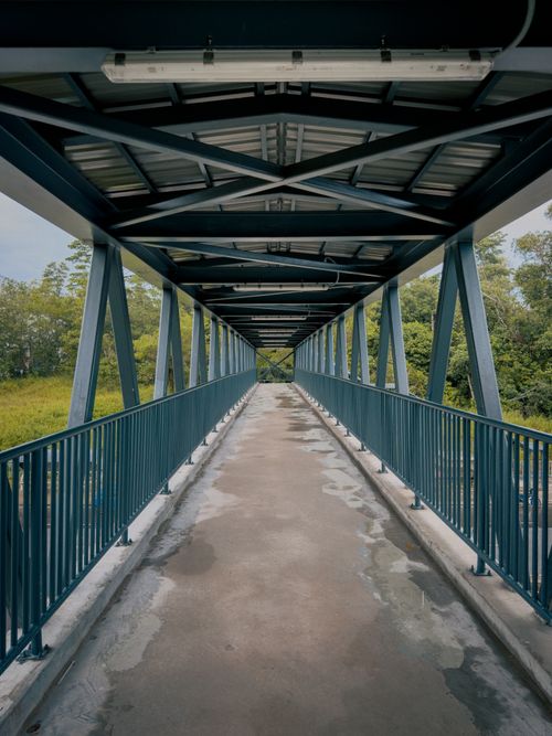 Free Symmetrical view of a pedestrian bridge in Kuching, showcasing modern architecture and serene surroundings. Stock Photo