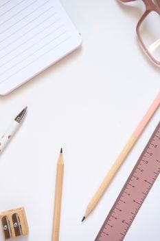 Flat lay of a modern workspace featuring pens, pencils, notebook, and ruler.
