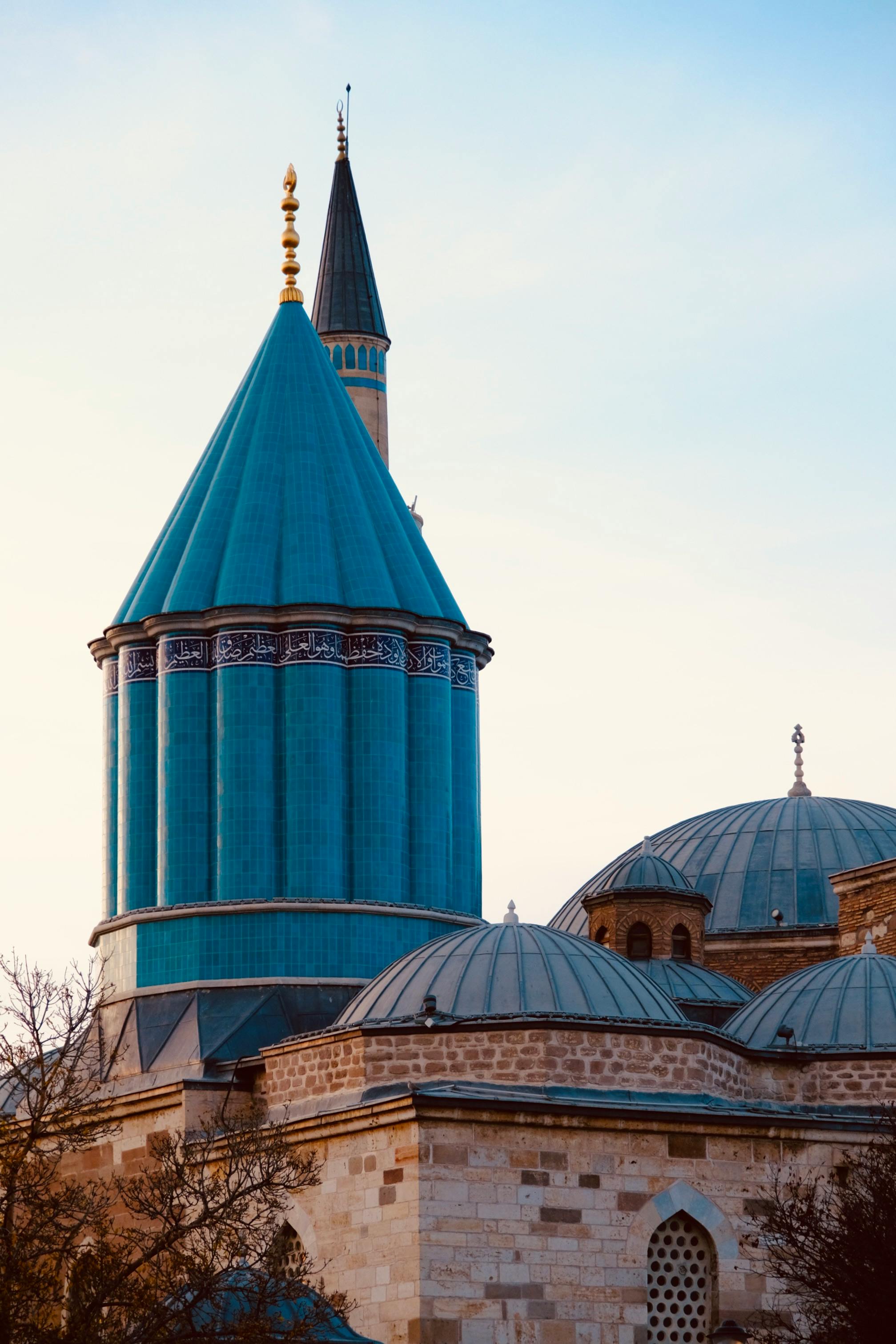 A vibrant view of the Mevlana Museum's unique architecture in Konya, Turkey, with its distinct turquoise dome.