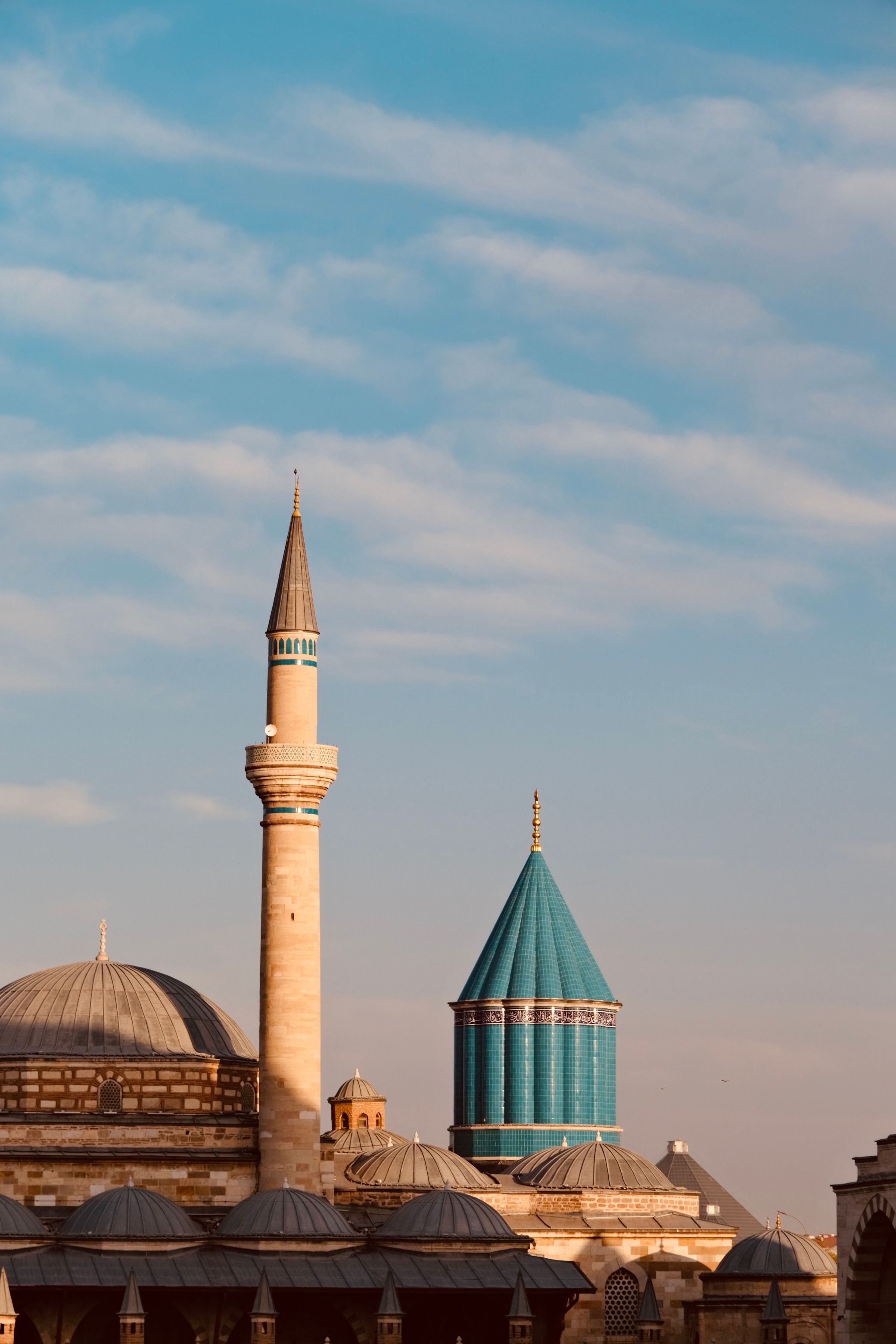 The distinctive blue dome and minaret of the Mevlana Museum in Konya, Turkey, under a bright sky.