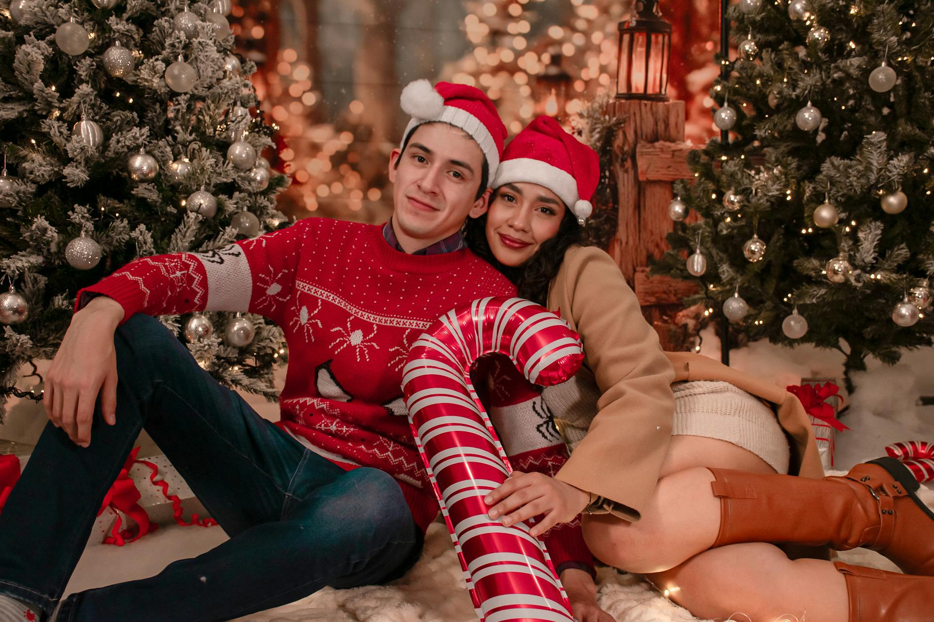 A joyful couple wearing Santa hats enjoys Christmas surrounded by festive decorations indoors.