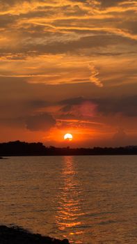 Beautiful sunset casting an orange glow over calm lake waters.