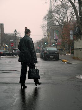 A fashionable woman walks down a snowy urban street in Longueuil, Quebec during winter.