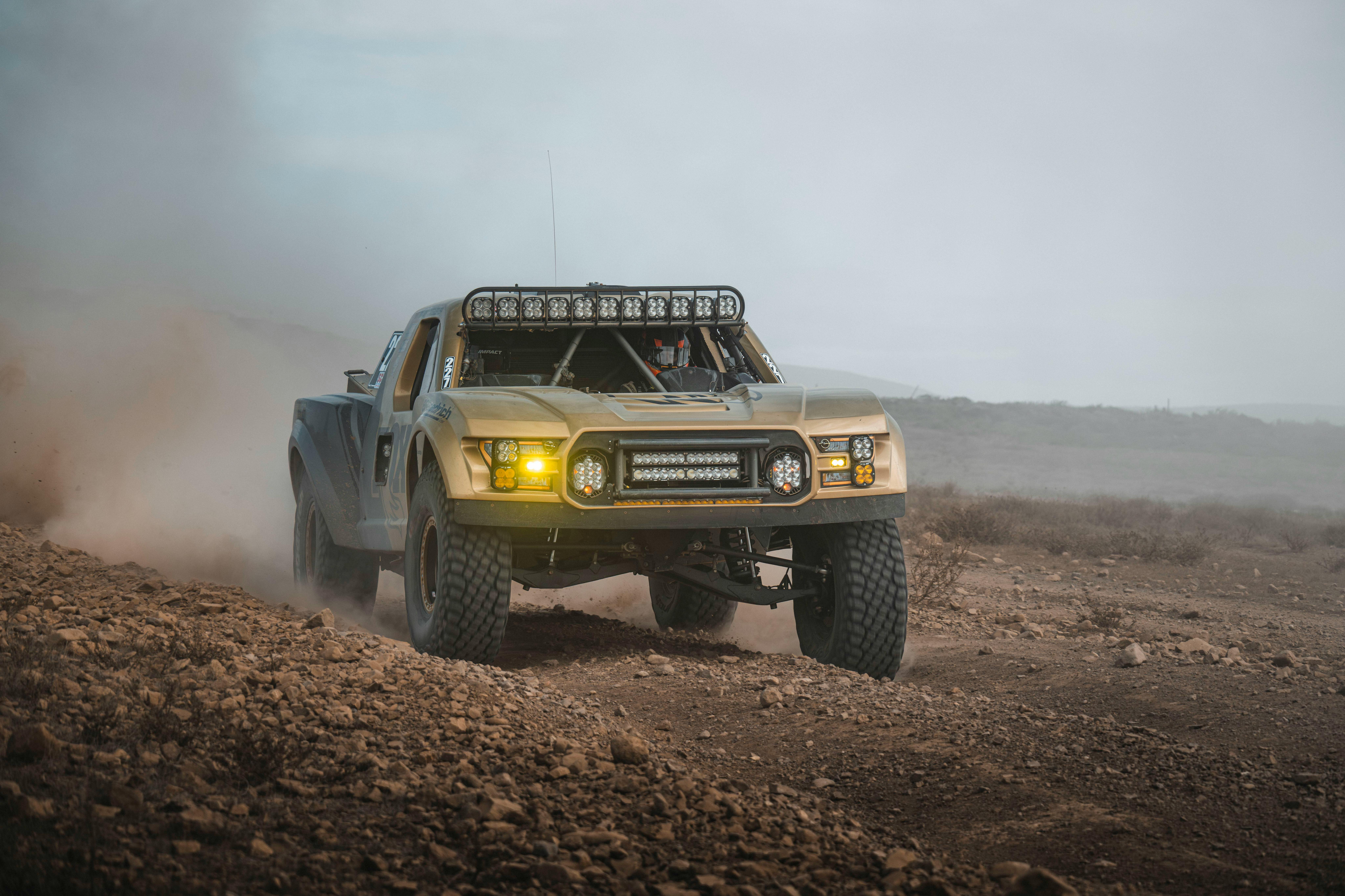 Dynamic shot of a powerful off-road truck racing in the Baja California desert, kicking up dust.