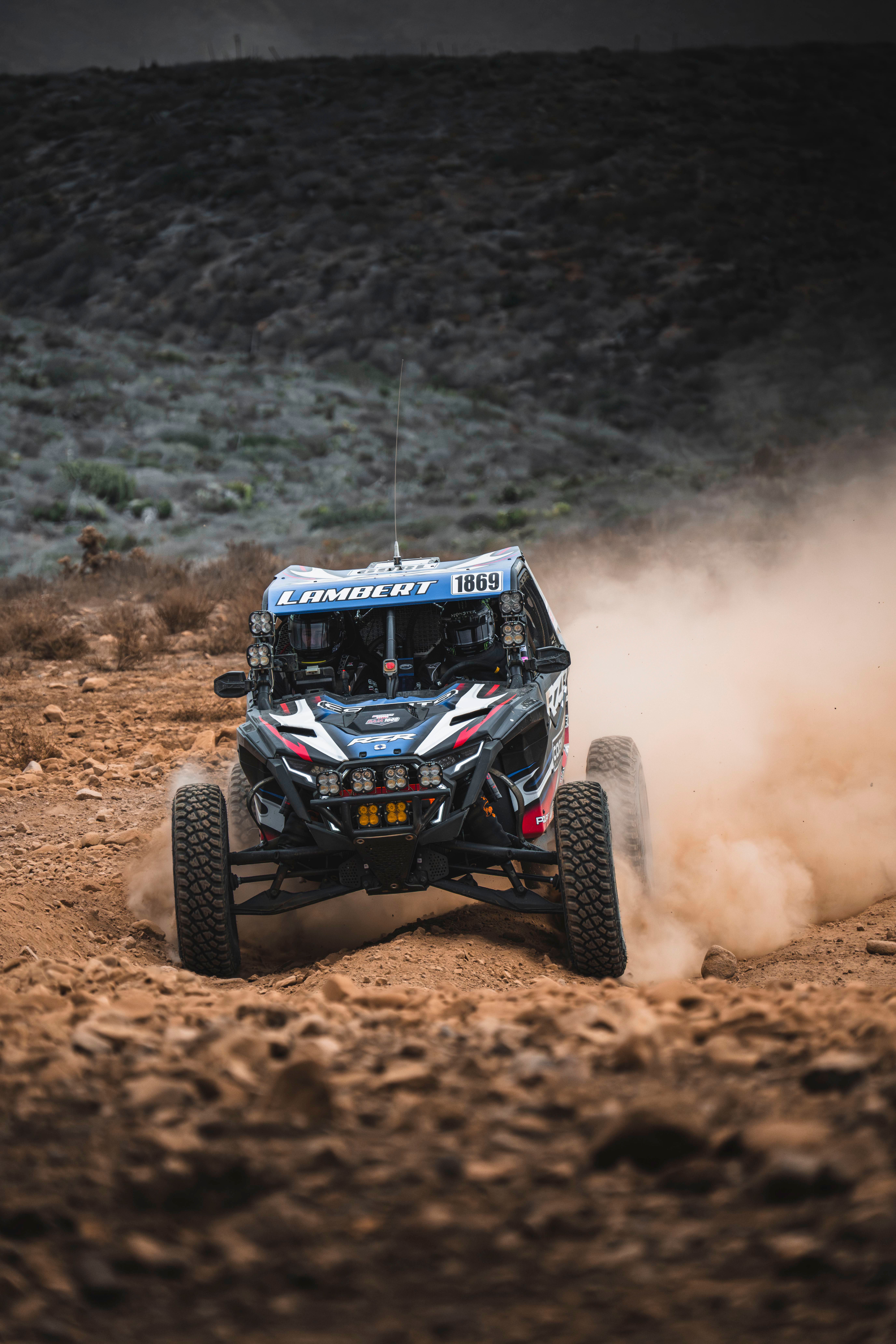 Intense off-road racing in Baja California with a trophy truck kicking up dust on rugged terrain.