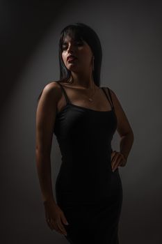 Portrait of an elegant woman in black dress with mysterious lighting.
