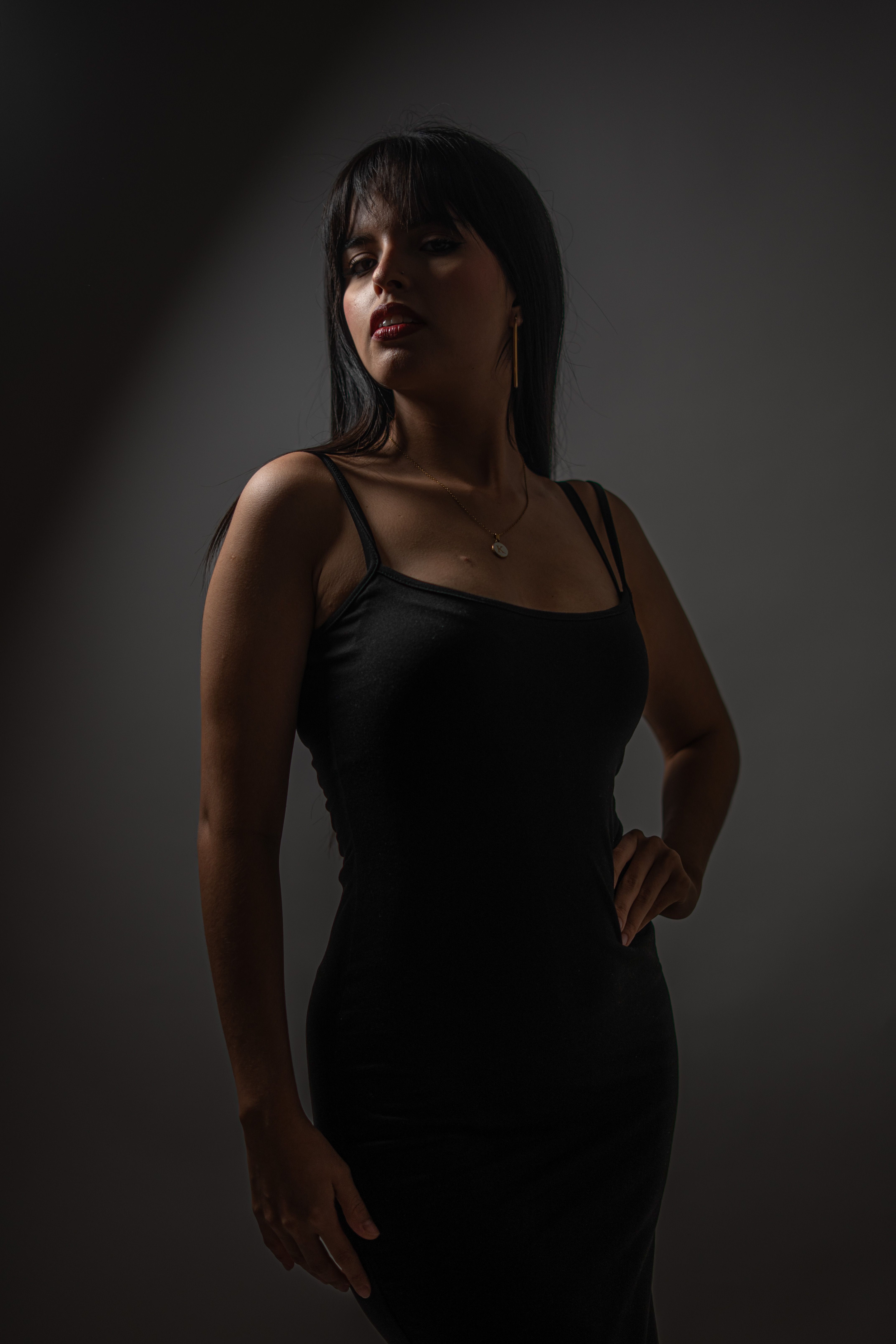 Elegant Woman in Black Dress Against Dark Background · Free Stock Photo