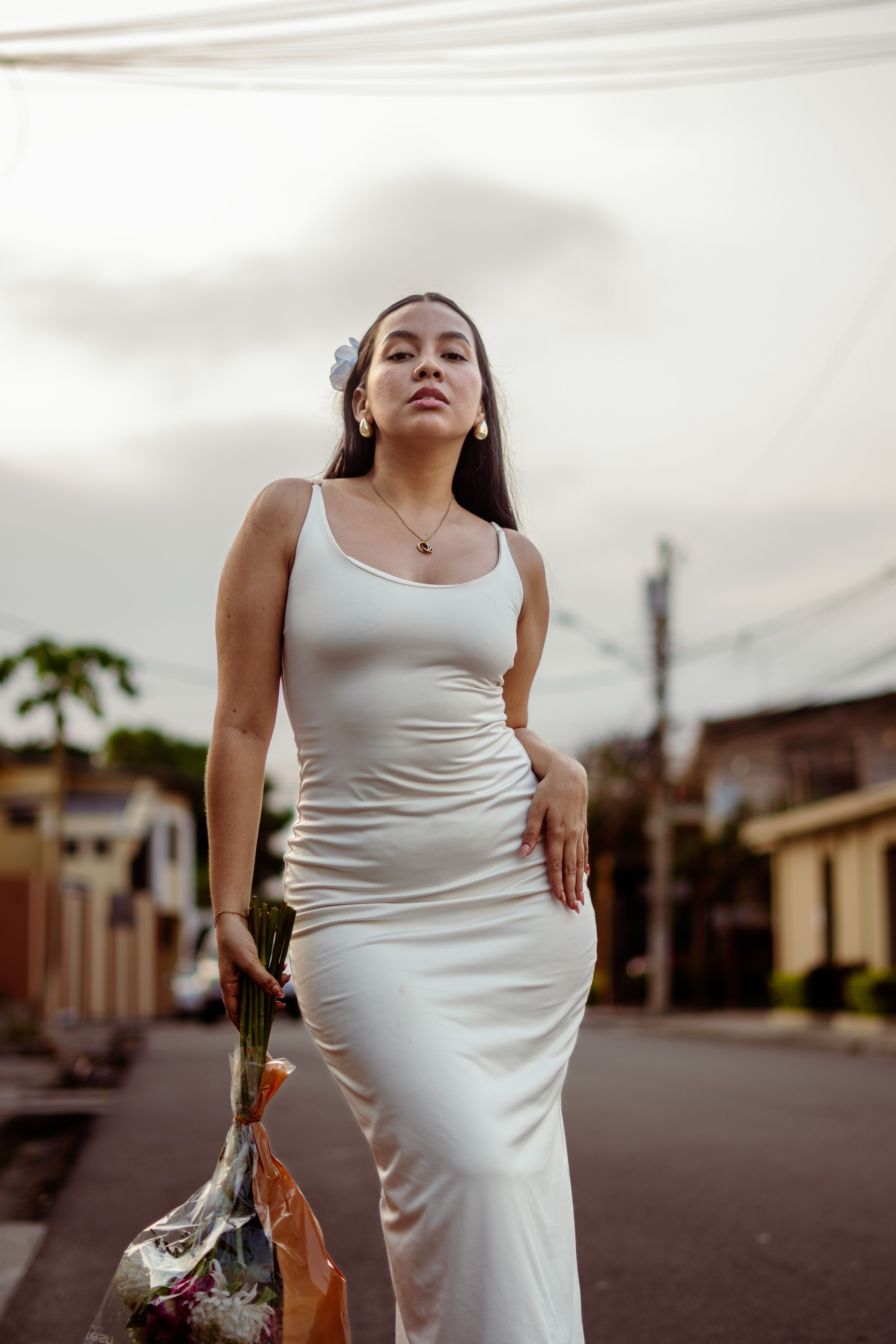 Elegant Woman in White Dress Holding Flowers Outdoors · Free Stock Photo