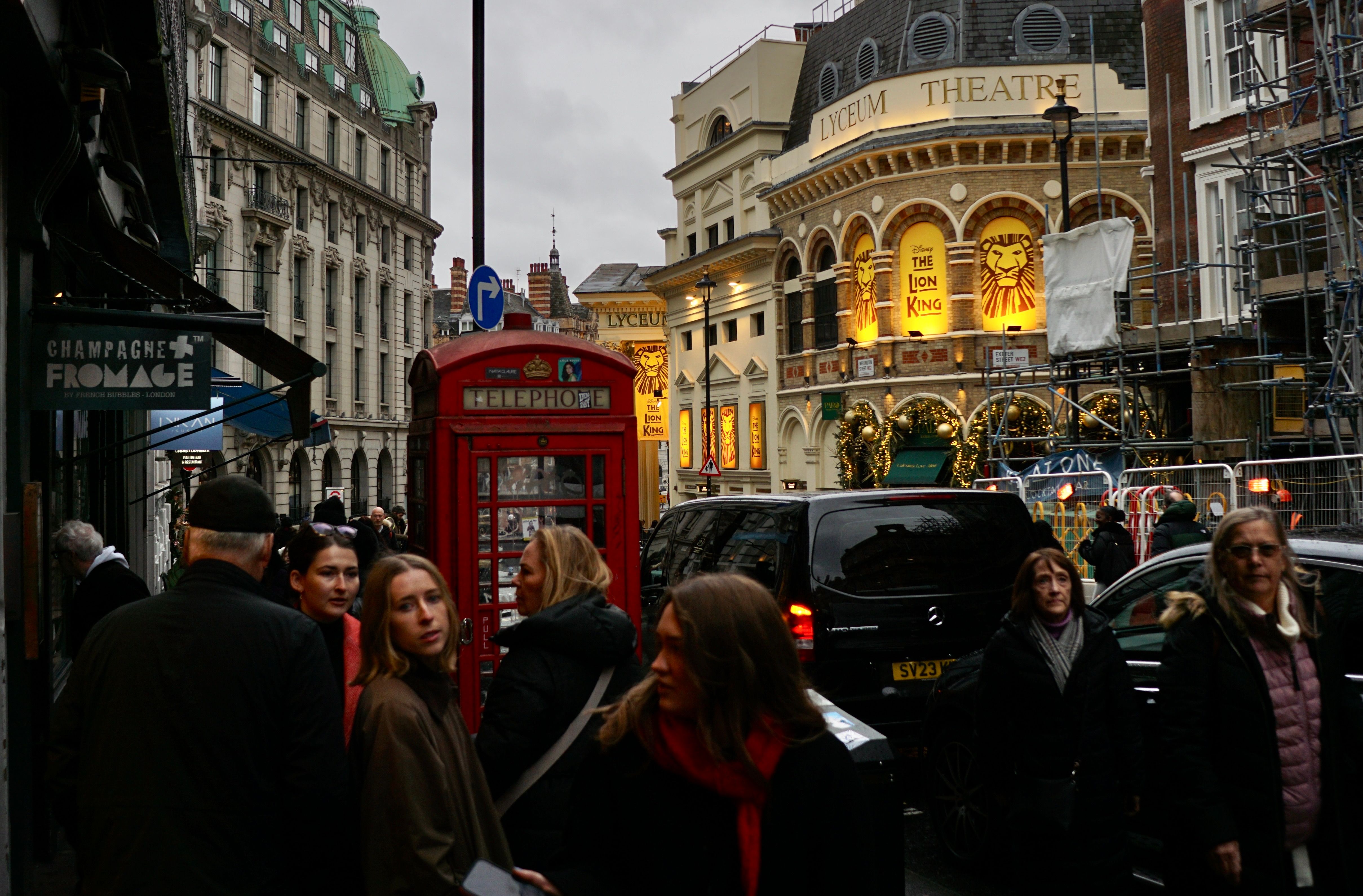 Crowded London street featuring iconic red telephone booth and Lyceum Theatre.