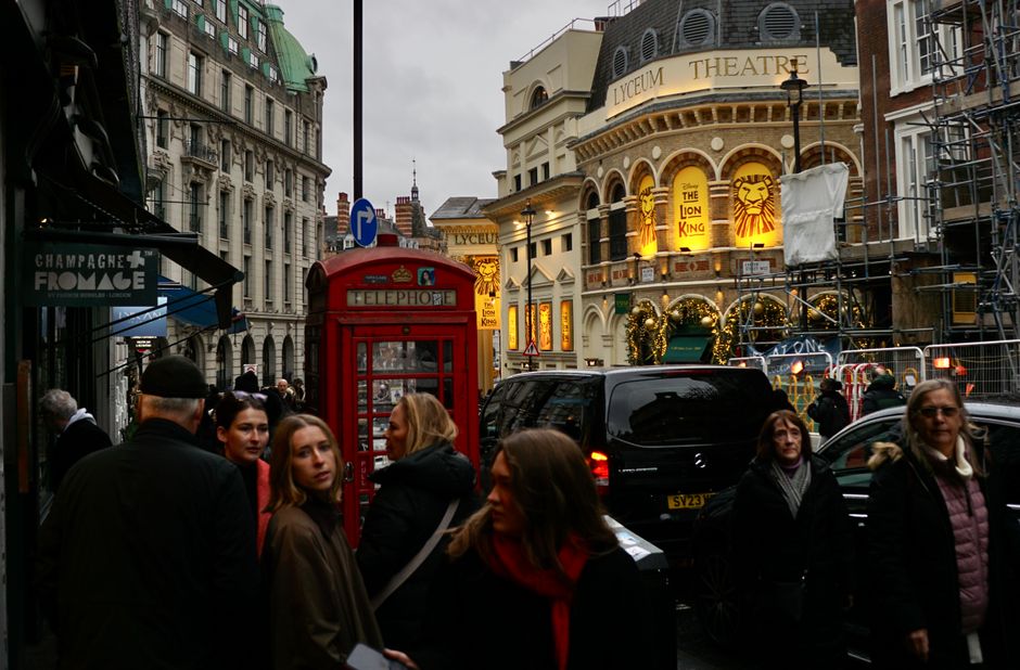 Crowded London street featuring iconic red telephone booth and Lyceum Theatre.