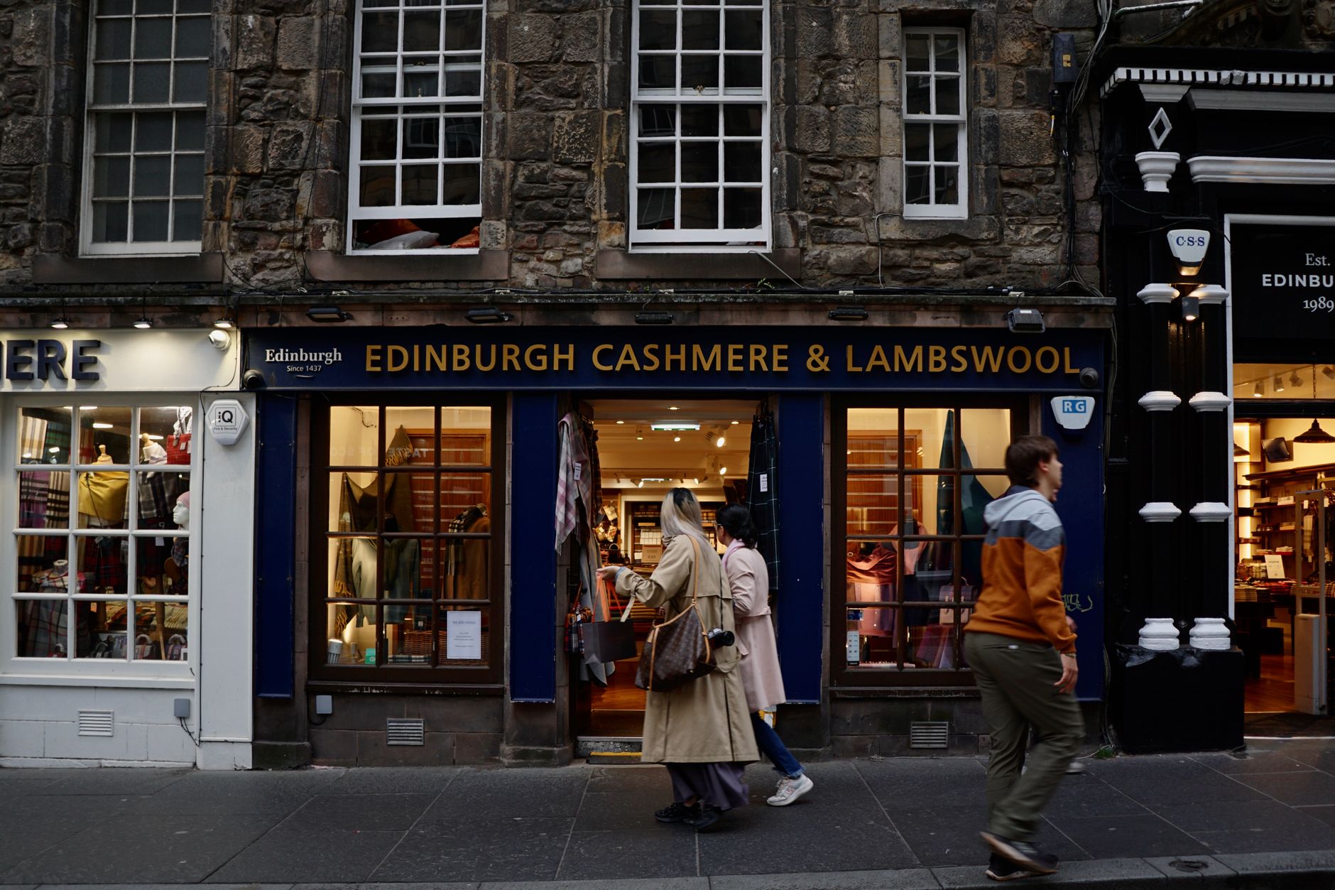 People walking past Edinburgh Cashmere & Lambswool shop, showcasing urban fashion scene.