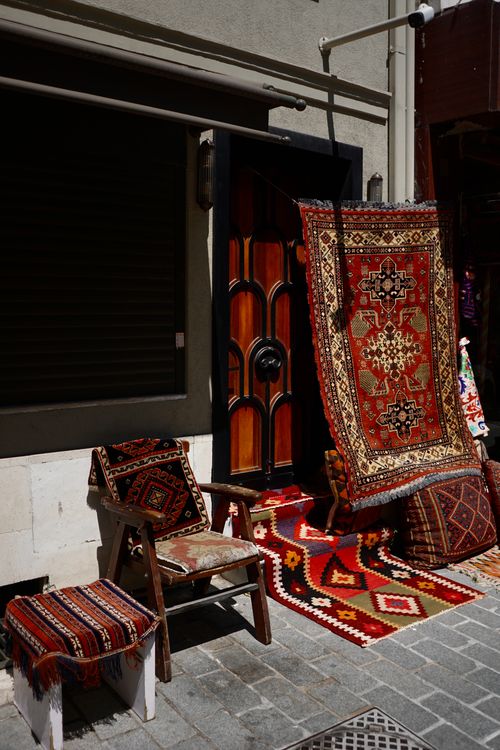Free Colorful Turkish rugs and cushions displayed in a bazaar setting, highlighting rich patterns. Stock Photo