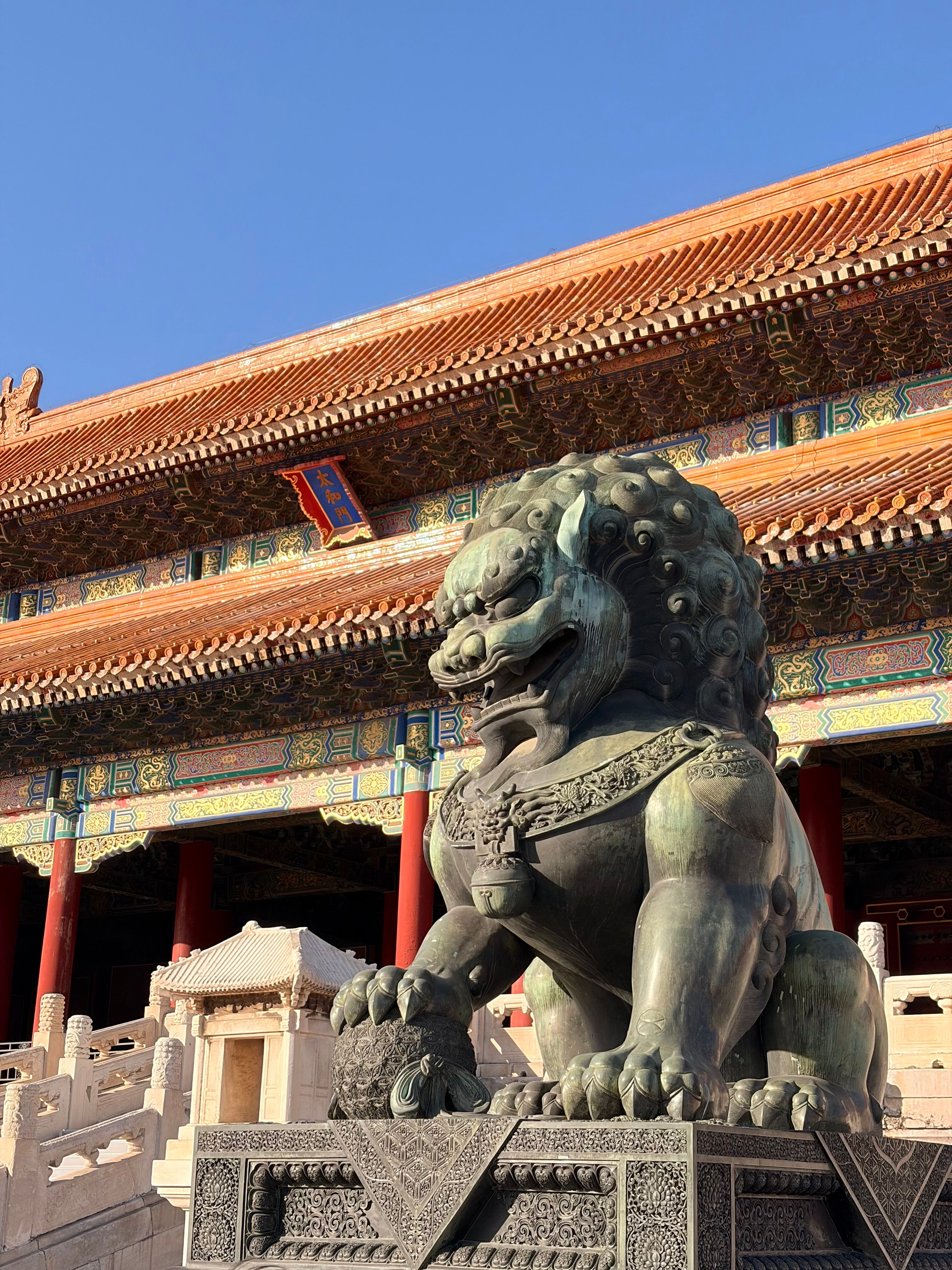 Statue of a Guardian Lion at the Forbidden City in Beijing under clear blue sky.