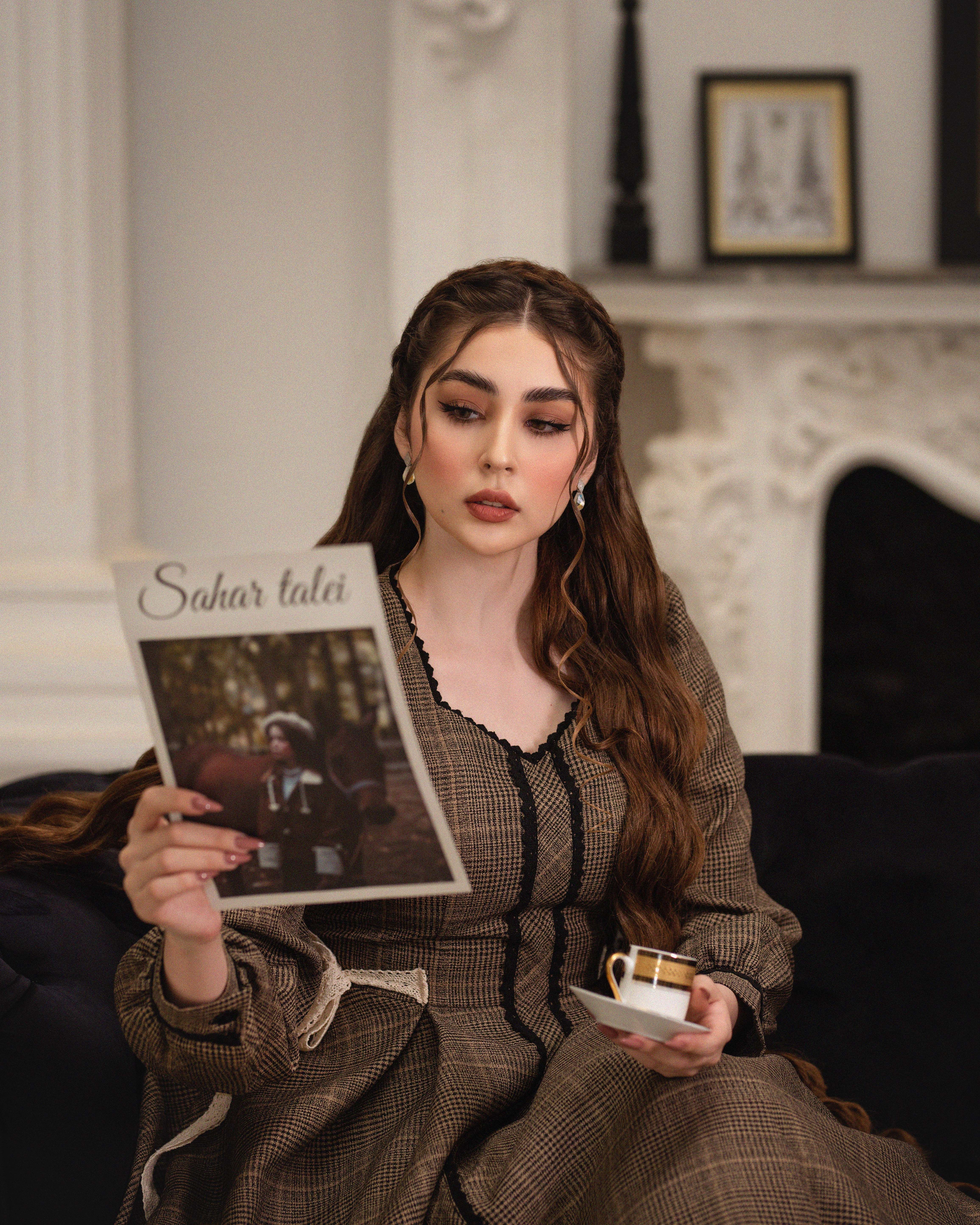 Stylish woman in vintage attire reading a magazine indoors, capturing a classic and elegant vibe.