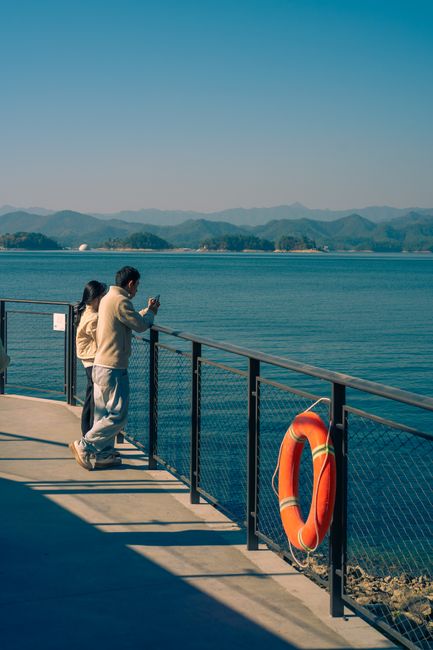 Couple on a scenic waterfront with mountains and clear skies at Qiandao Lake, Hangzhou, China.