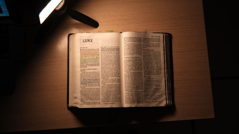 An open Bible on a desk under a lamp