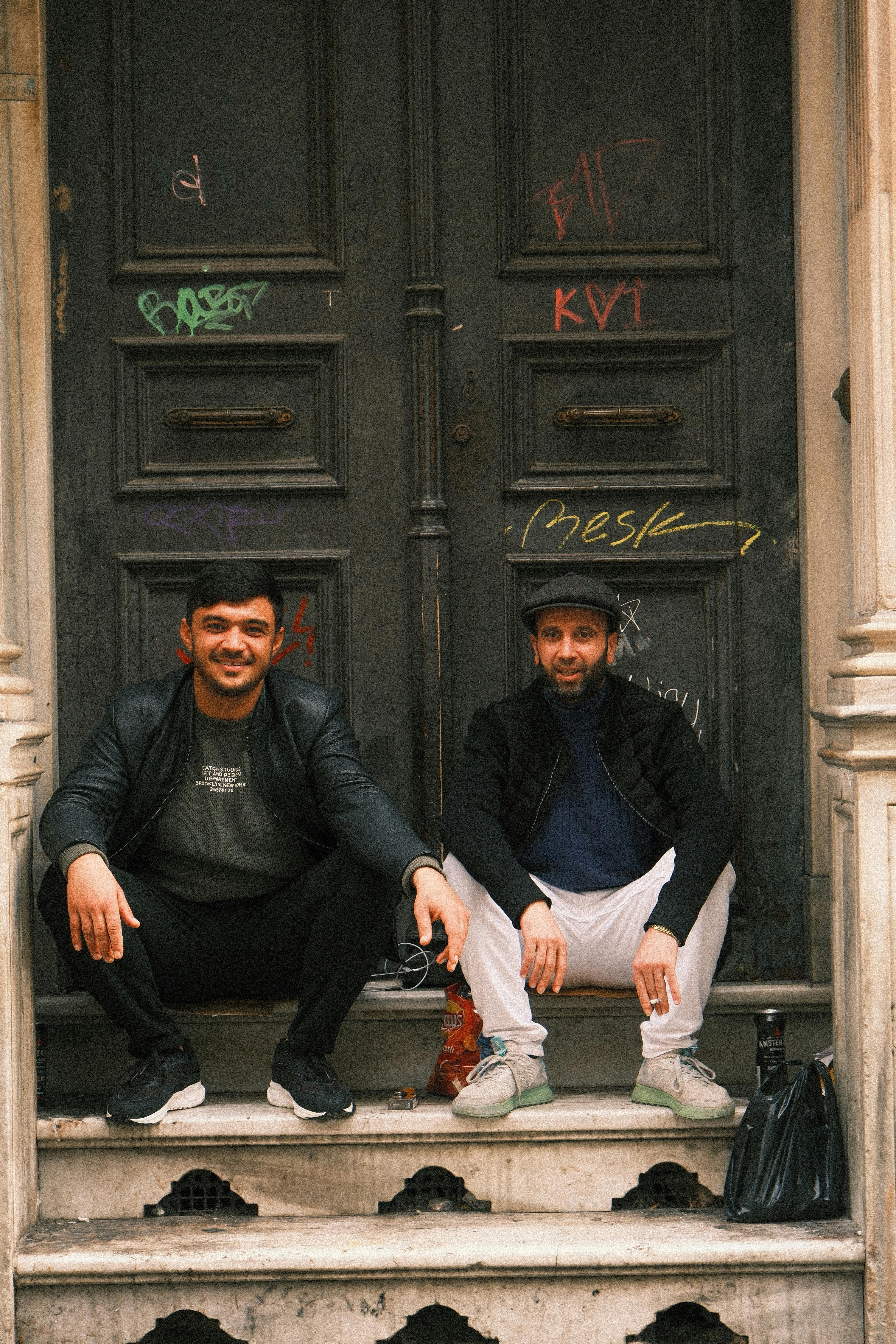 Two men sitting on steps in İstanbul, capturing a casual urban vibe. Perfect for lifestyle themes.
