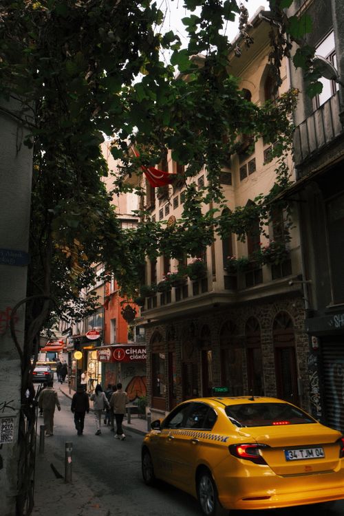 Free A lively İstanbul street featuring a yellow taxi and walking pedestrians surrounded by traditional architecture. Stock Photo