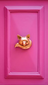 Striking pink door featuring a gold fox knocker, blending playful and modern design.