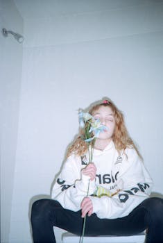 一位年轻女子坐在室内，闭着眼睛，手拿鲜花