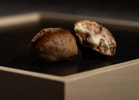 Detailed image of a roasted chestnut showcasing texture and layers on a wooden surface.