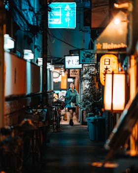 Explore a lively Osaka alley at night featuring neon lights and a pedestrian amidst shops.