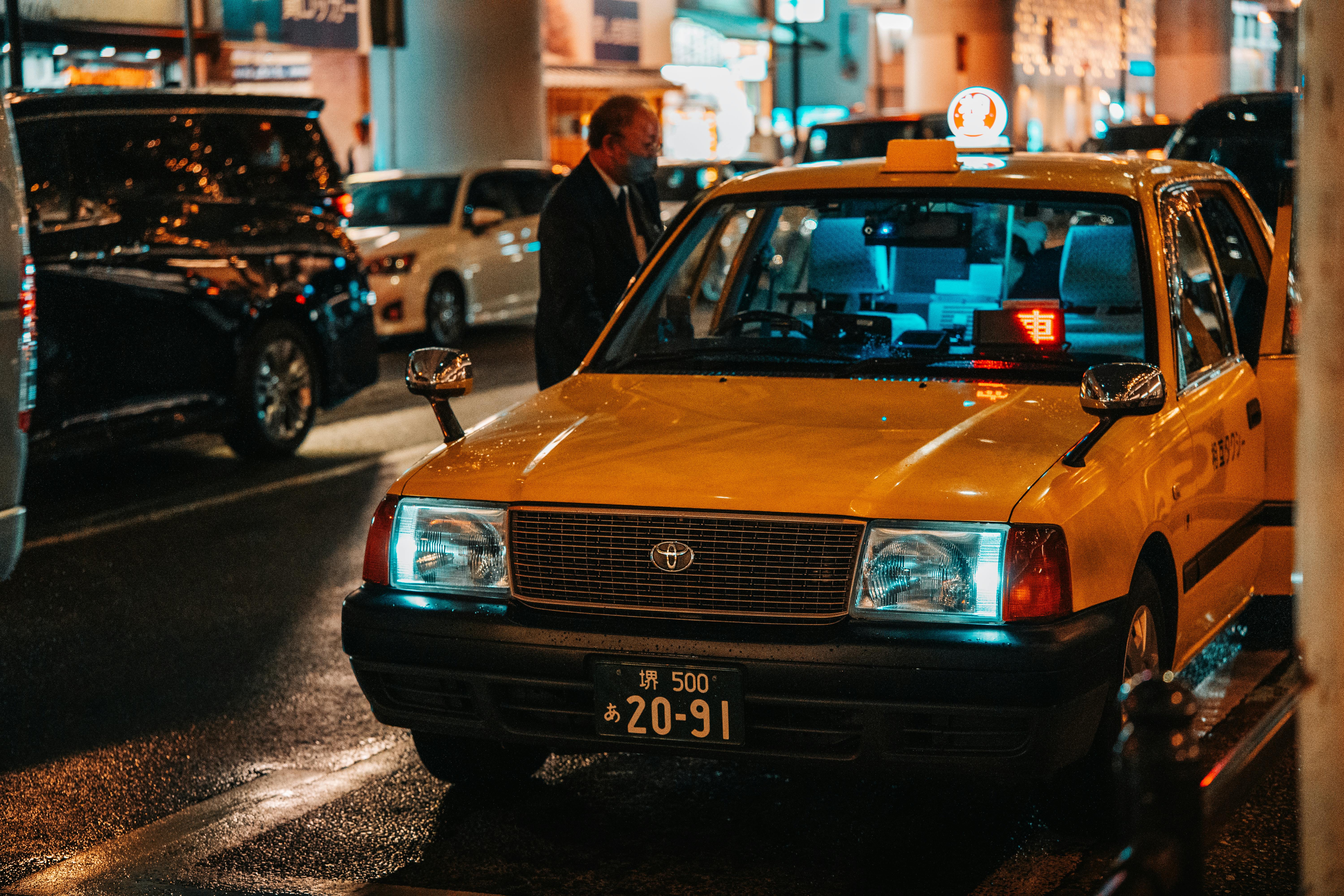 A vibrant night scene of a yellow taxi in Dotonbori, Osaka, capturing the city's lively atmosphere.
