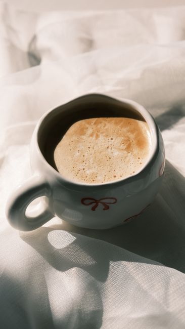 Warm cup of frothy coffee in a decorative mug on soft fabric, capturing tranquility.