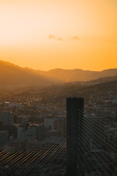 A breathtaking view of Osaka's cityscape during sunset, showcasing urban architecture and distant mountains.