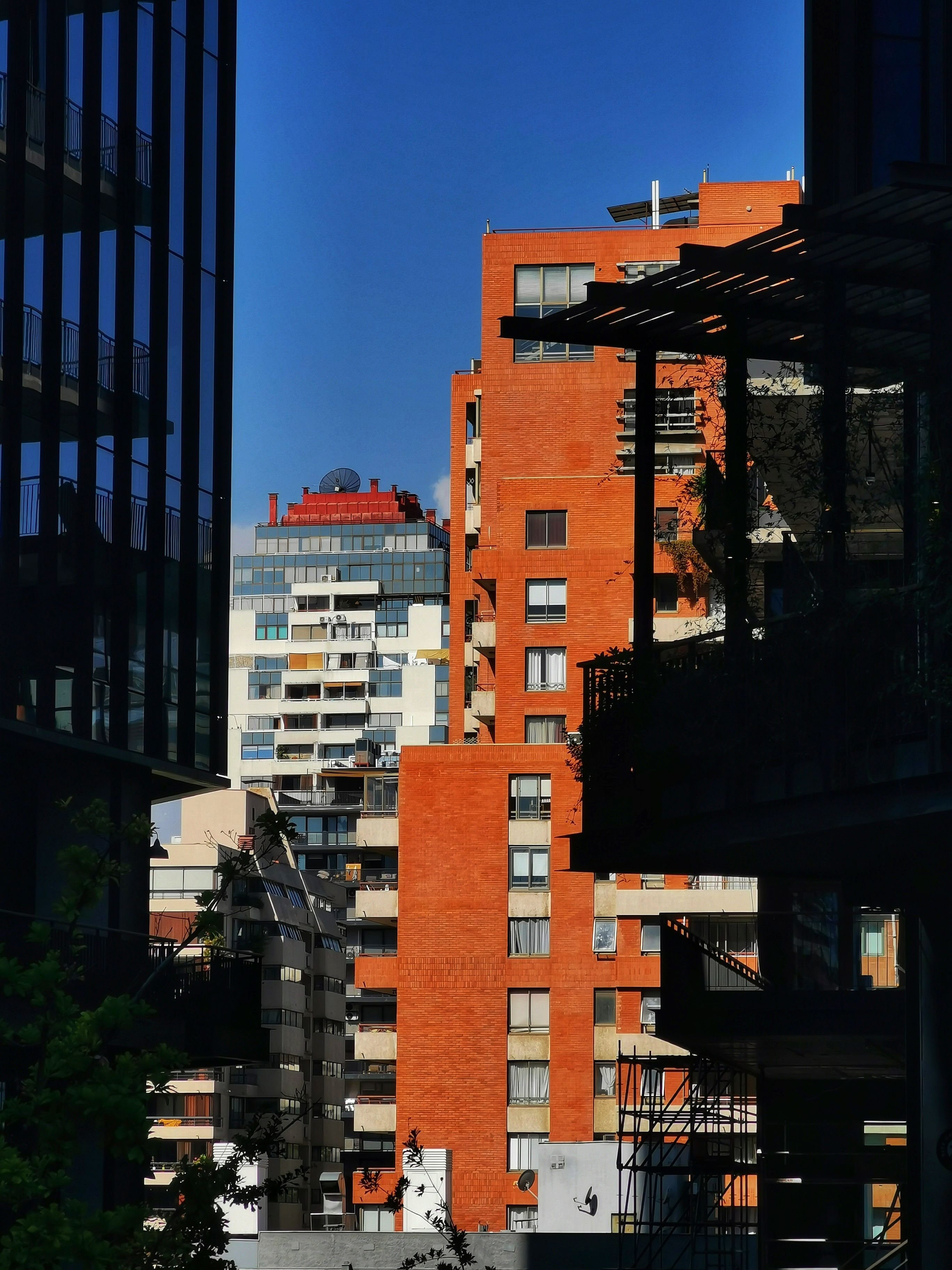 View of red brick buildings in a vibrant city under a clear blue sky.